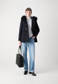 Jūrų laivyno paltas su dirbtiniu kailiu apykakle, vienos krūtinės uždarymas, derinamas su baltu raštuotu megztiniu ir šviesiai mėlynomis džinsinėmis kelnėmis. Juoda rankinė ir kulkšnies auliniai batai.