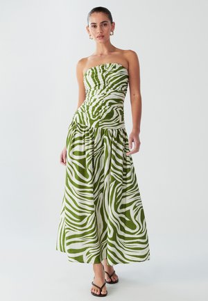 Green and white striped strapless dress with ruched bodice, flowing skirt, and textured fabric. Styled with black sandals.