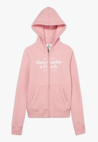 Roze hoodie met ritssluiting, gemaakt van zachte stof, voorzien van een capuchon, twee voorzakken en een wit tekstlogo op de borst.