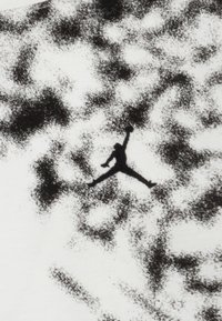 White fabric with a black silhouette of a leaping figure centered on a speckled black and gray background, showcasing a dynamic design.