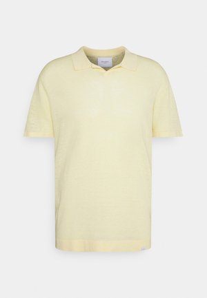 Polo a maniche corte giallo pallido con colletto morbido e texture sottile, mostrata su sfondo bianco.