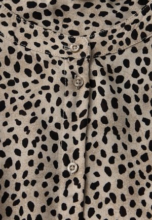 Beige blus med svart djurmönster, med knäppning fram, rund halsringning och slät tygstruktur. Knapparna är ljusa.
