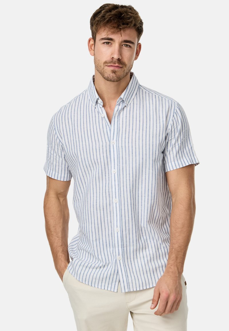 Camisa de manga corta a rayas en azul claro y blanco, hecha de tela ligera. Presenta un collar con botones y botones en la parte frontal.