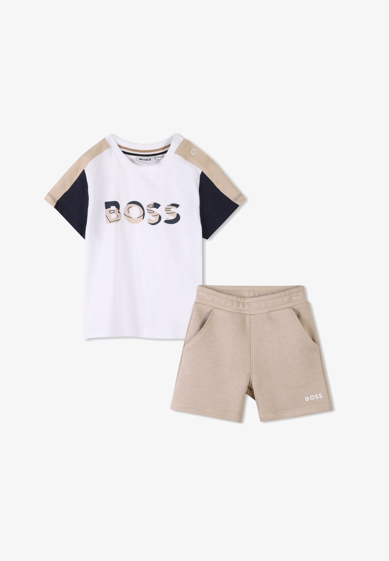 Witte T-shirt met marineblauwe en beige accenten, met de tekst "BOSS" in een patroonlettertype. Beigekleurige shorts met voorkruiszakken en logo-detail.