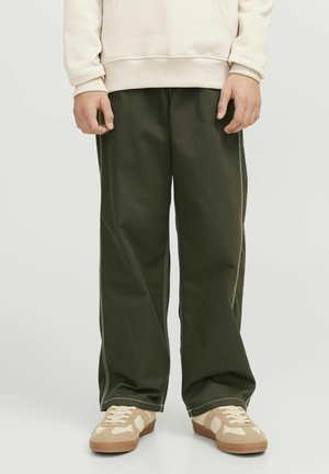 Groene wijde broek met contrasterende witte stiksels, gecombineerd met beige schoeisel met een textuur bovenwerk en rubberen zool.