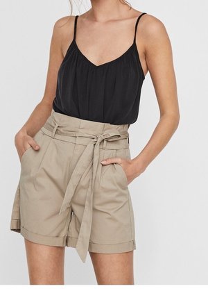 Un débardeur noir à décolleté en V associé à un short beige taille haute avec une ceinture et des poches latérales, fabriqué en tissu léger.