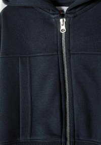 Námornícka mikina na zips z jemnej textúrovanej látky s centrálnym kovovým zipsom a rebrovanými manžetami. Podrobné prešitie pozdĺž švov.