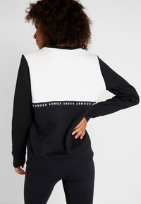 Sudadera en blanco y negro con un diseño de bloques de color, fabricada en tejido suave, con puños y dobladillo acanalados, y una banda con el logotipo en la cintura.