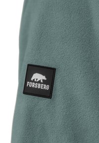 Licht teal fleece stof met een gestructureerde uitstraling. Heeft een zwart rechthoekig embleem met een berenafbeelding en de tekst "FORSBERG".