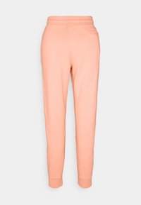 Light peach jogging pants made of soft cotton blend, featuring a ribbed waistband, tapered cuffs, and diagonal seam detailing.