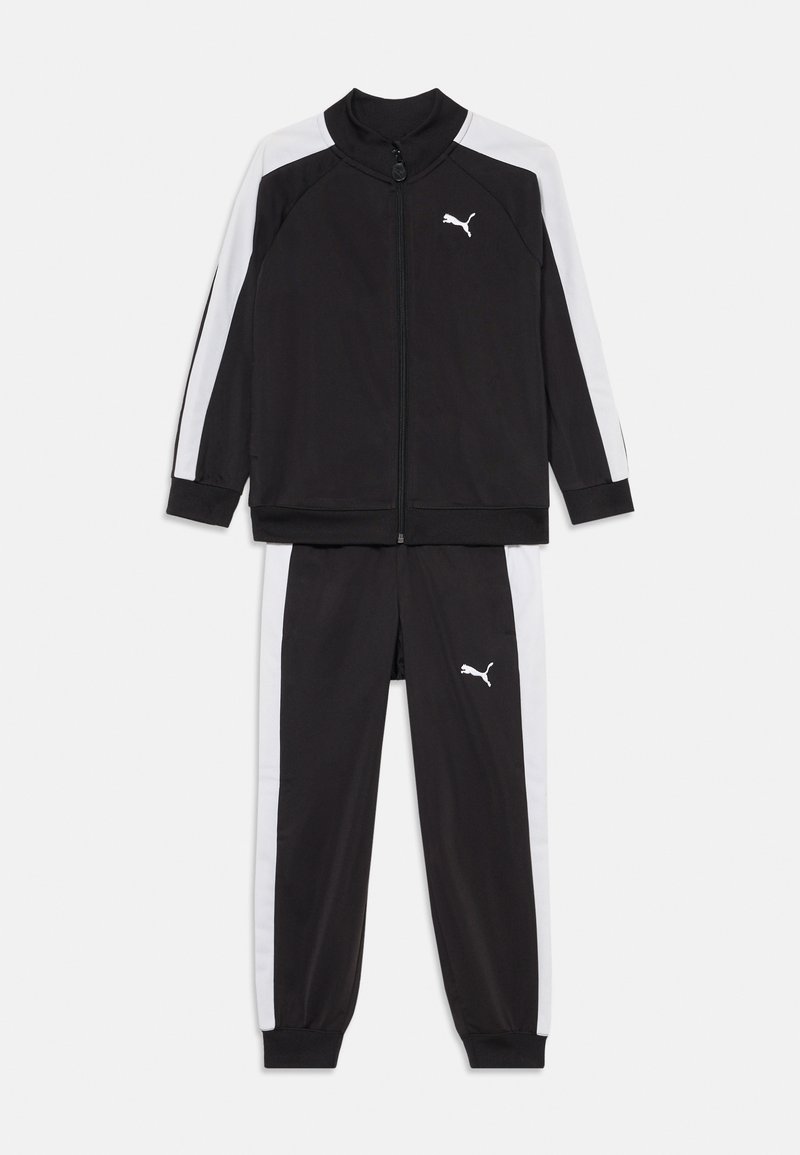 Melna sporta treniņtērps ar baltām sānu svītrām, kas sastāv no slēdzama jakas un saskaņotām biksēm. Izgatavots no gludas, vieglas auduma.