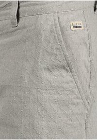 Grå texturerade shorts med ett subtilt geometriskt mönster, framfickor och en vävd etikett på midjan märkt "BLEND."