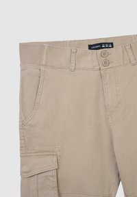 Beżowe spodnie cargo wykonane z bawełny o miękkiej teksturze, z dwoma przednimi kieszeniami, elastycznym pasem i dwoma zapięciami na guziki.