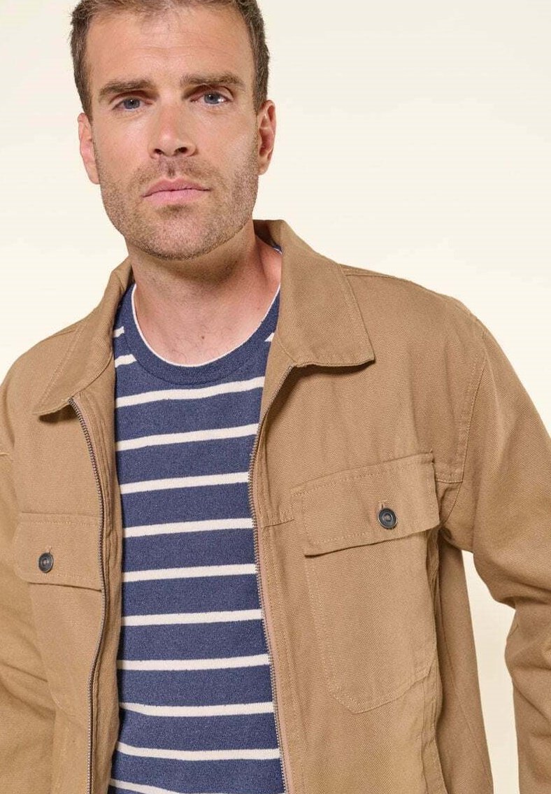 Bruine ritsjack met twee voorzakken, gedragen over een marineblauw gestreept shirt. De jas heeft een kraag en een gestructureerd materiaal.