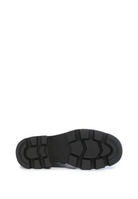 Suela de bota de goma negra con patrones de relieve angulares y profundos, diseñados para ofrecer tracción y durabilidad.
