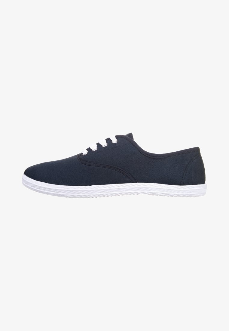 Baskets décontractées en toile noire avec lacets blancs et semelle en caoutchouc blanche, vues de profil sur un fond blanc.