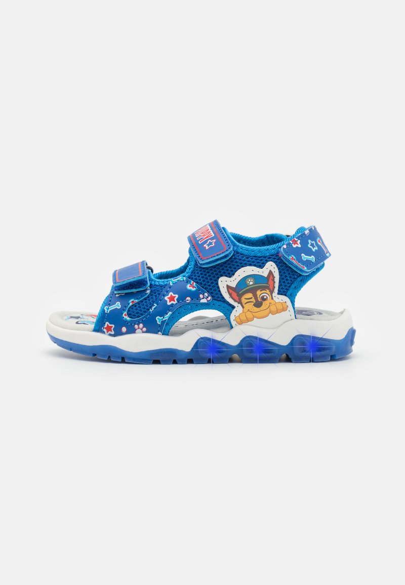 Sandale en mesh bleue avec des sangles ajustables, semelle en caoutchouc et accents lumineux. Présente un design de personnage de dessin animé et des motifs de traces de pattes.