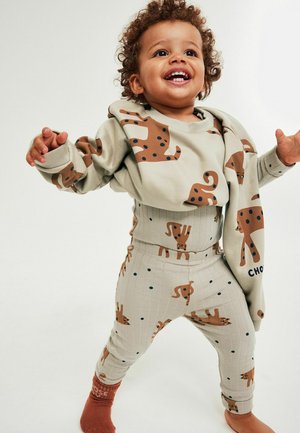 Beige babyoutfit med langærmet top med brune hundemønstre og matchende ribbede bukser med prikker og hundemotiver.