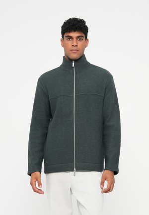 Mörkgrön fleecejacka med hög krage, dragkedja fram och ribbad mudd. Har en texturerad yta och horisontella sömdetaljer.