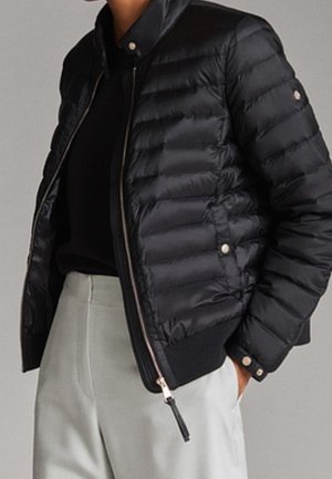 Black padded jacket with a stand collar, zip closure, and side pockets. Features shiny fabric, ribbed cuffs, and a smooth texture.