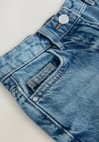 Shorts en denim bleu clair avec un lavage délavé. Les caractéristiques comprennent une poche avant, un bouton en métal et des coutures contrastées.