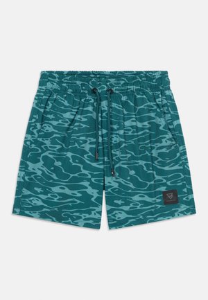 Short de bain sarcelle avec motif ondulé bleu clair, taille élastique, cordon de serrage, poches latérales et petit patch logo sur la jambe gauche.