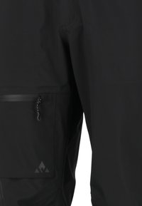 Pantalons d'extérieur noirs en matériau léger, dotés d'une poche zippée sur le côté et d'un logo discret près de l'ourlet.