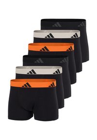 Zes paar zwarte heren boxershorts in twee kleurpatronen: oranje tailleband met zwart logo en beige tailleband met zwart logo, gerangschikt in verspringende rijen.