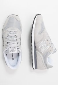 Baskets New Balance grises avec un mélange de matériaux en maille et en daim, bout arrondi, lacets et une semelle extérieure en caoutchouc noir.