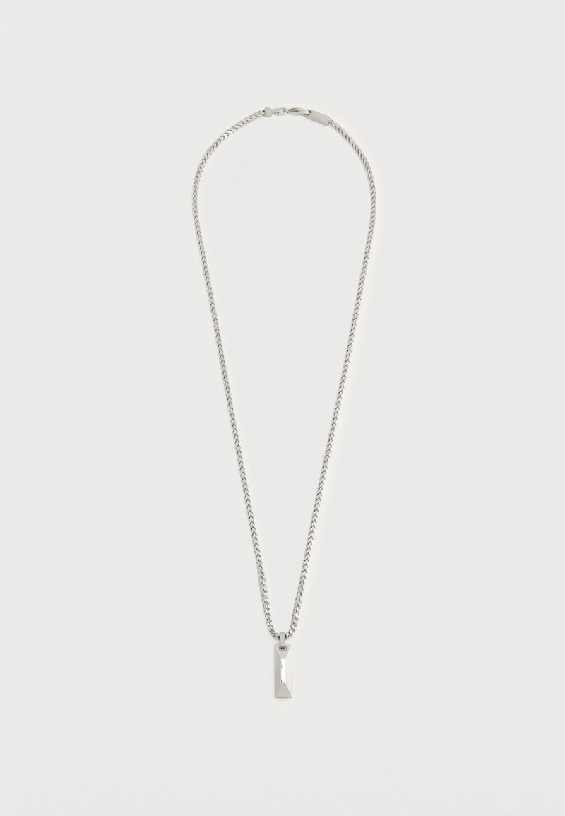Collier chaîne ton argent avec un pendentif rectangulaire et plat suspendu au centre sur un fond blanc uni.