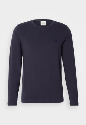 Jūros laivyno ilgomis rankovėmis medvilninė marškinėliai su apvaliu iškirpimu ir minimalistiniu Calvin Klein logotipu ant krūtinės. Sklandus audinys ir liesas siluetas.