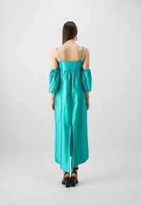 Hosszú, teal színű, selymes ruha off-the-shoulder puff ujjú, hátsó hasítékkal és állítható vékony pántokkal. Simára szabott textúra és testhezálló fazon.