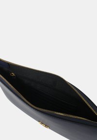 Clutch in pelle blu navy con zip dorata. L'interno presenta una fodera nera, slot per carte e una piccola tasca con zip per un sicuro stoccaggio.