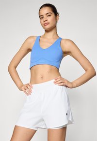 Sutiã de desporto azul com design em V e logótipo, combinado com calções de atletismo brancos com cintura elástica e racha lateral.