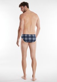 Herren-Schwimmbadehosen in Navyblau mit Karomuster. Weicher Stoff mit eng anliegender Passform, elastischem Bund und minimaler Bedeckung am Rücken.