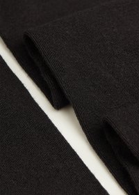 Czarna dzianina o gładkiej teksturze, z dwiema nakładającymi się sekcjami, które prezentują równomierne przeszycia oraz miękki, ciepły wygląd.