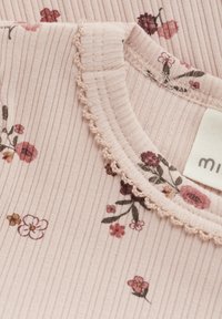 Ribbat rosa tygtop med ett blommigt mönster med små blommor i olika nyanser. Utsmyckad med en scalloped halsringning och etikett.