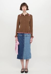 Hnědý žebrovaný cardigan s růžovými detaily, peplum spodním lemem a knoflíky, v kombinaci s džínovou sukní s různými modrými odstíny a předním rozparkem.