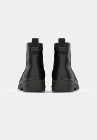 Svarta läderankelstövlar med en slät yta, rund tå och en låg träklack, med en dragflik bak för enkel påtagning.