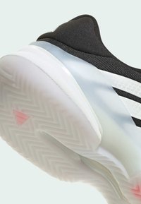 Μαύρο αθλητικό παπούτσι με υφή ανώτερο, ημιδιαφανή σόλα και λευκά στοιχεία. Διαθέτει σχέδιο ψαροκόκαλο και ροζ λεπτομέρεια στη σόλα.