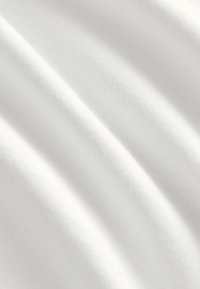 Tessuto bianco liscio con pieghe morbide e trama sottile visibile in primo piano.