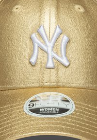 Goldfarbener Metallverschluss mit einem weißen gestickten "NY"-Logo. Ausgestattet mit einem verstellbaren Rücken und einem runden Etikett mit der Aufschrift "9FORTY WOMEN."