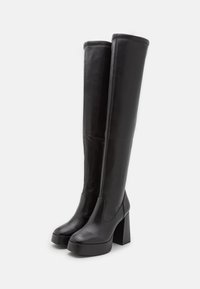 Black over-the-knee boots made of smooth leather, featuring a chunky heel and platform, with a side zipper for easy wear.