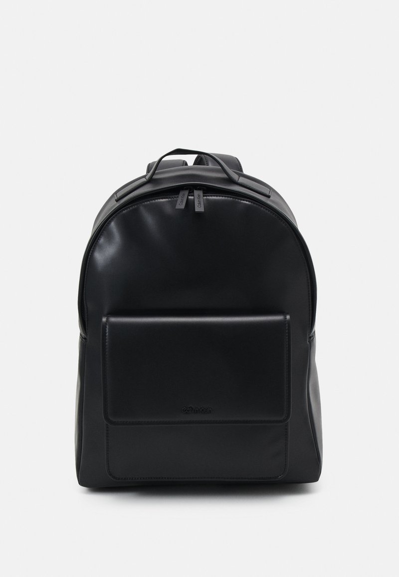 Schwarzer Leder-Rucksack mit runder Form, Vordertasche, doppelten Reißverschlusszips und Logodetail am Boden. Glatte Textur.