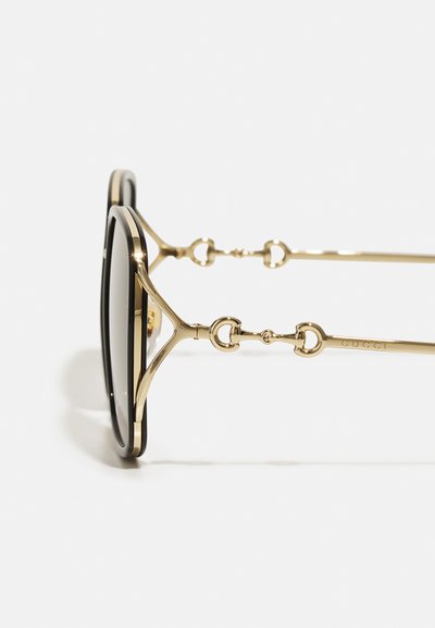 Gold metal sunglasses with black lenses, featuring a structured frame, decorative hardware at temples, and a smooth finish.