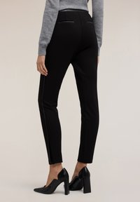 Zwarte tailored broek met een slim fit, voorzien van zijkanten met accenten, ritsdetails aan de zoom en nep leren achterzakken.