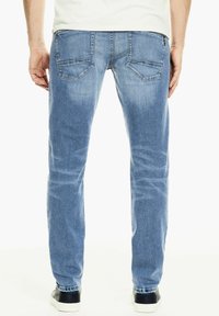 Světle modré džíny s rovným střihem, které mají dvě zadní kapsy a jemné vyblednutí. V kombinaci s černo-bílými teniskami.