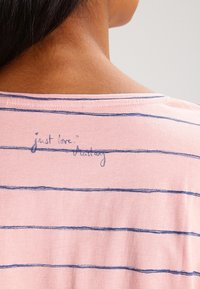 Růžová pruhovaná košile se modrými vodorovnými pruhy, s potiskem na zadním výstřihu říkajícím „just love“. Měkký bavlněný materiál.