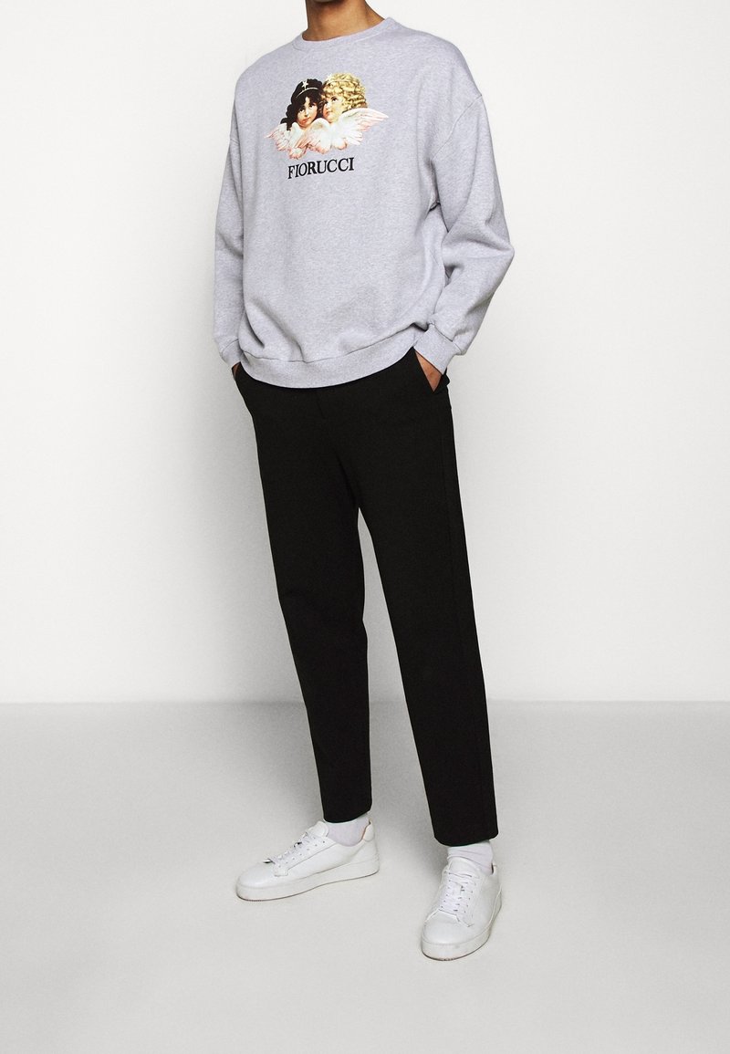 Sudadera gris con ángeles impresos y texto "FIORUCCI". Combinada con pantalones negros y zapatillas blancas; cuenta con un corte relajado y puños acanalados.