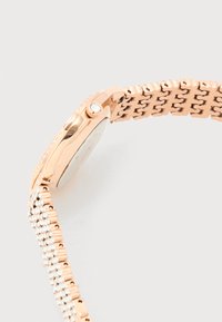 Πλευρική όψη ρολογιού σε χρώμα ροζ χρυσού που δείχνει το κορώνα με διαμάντια και ένα μεταλλικό βραχιόλι με ενσωματωμένους διαυγείς πολύτιμους λίθους.